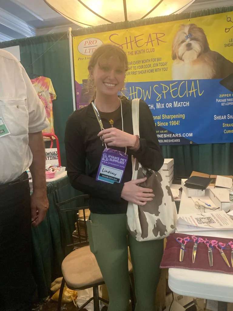 Woman holding bag at grooming expo booth.