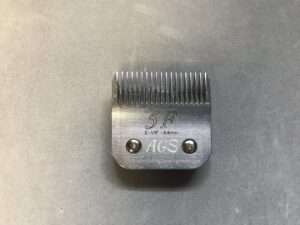 Stainless steel clipper blade on grey background.