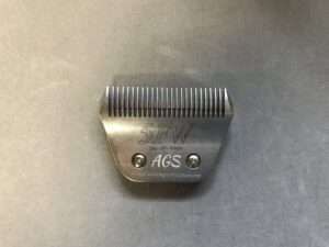 Stainless steel grooming blade on gray background.