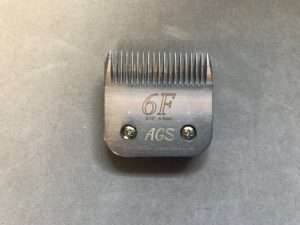 Metal hair clipper attachment on gray background.