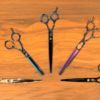 Various hairdressing scissors on wooden surface.