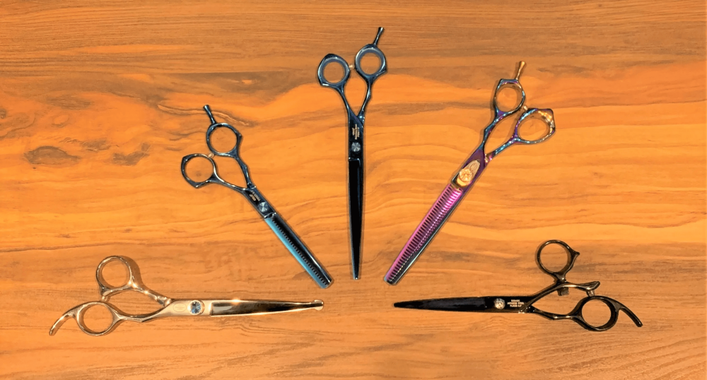 Various hairdressing scissors on wooden surface.