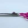 Pink hairdressing scissors on white background.