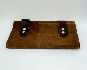 Brown suede clutch with leather straps and snap buttons.