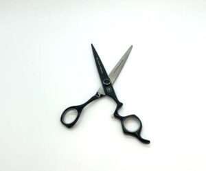 Professional black hairdressing scissors on white background.