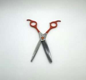 Orange-handled thinning shears on white background.