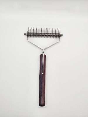 Metal dog grooming rake on white background.